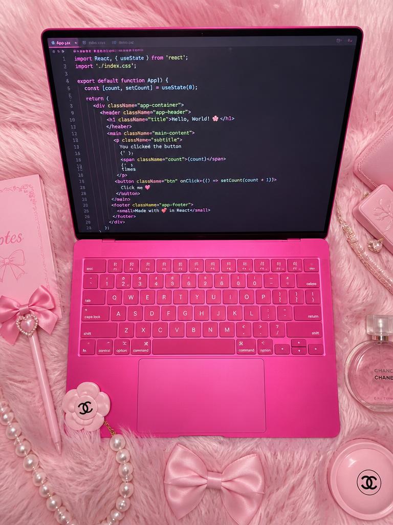 Pink laptop flatlay with code on screen, fluffy pen and bows